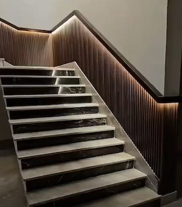 درج داخلي أنيق وعصري بتصميم راقٍ يجمع بين الرخام والخشب والإضاءة المخفية